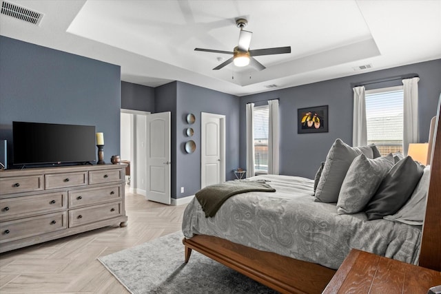 bedroom with a raised ceiling, multiple windows, baseboards, and ceiling fan