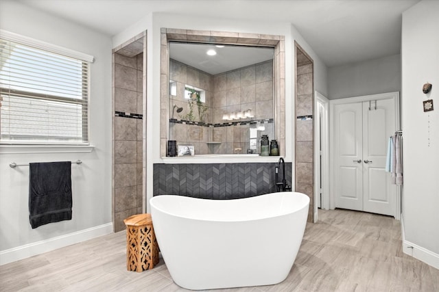 bathroom featuring a walk in shower, a freestanding tub, and baseboards