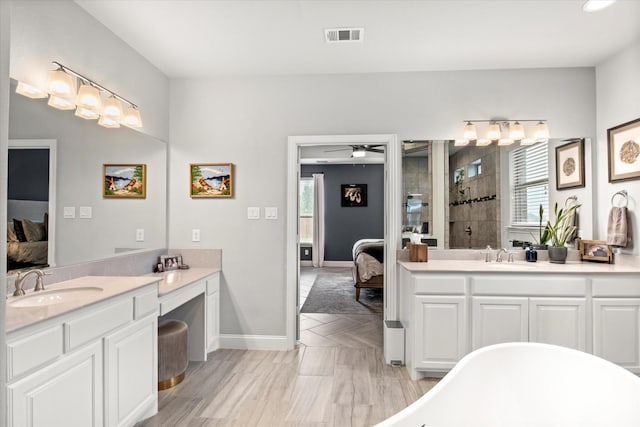 full bath featuring connected bathroom, plenty of natural light, a tile shower, and two vanities