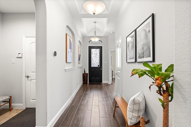 foyer featuring arched walkways, wood finished floors, and baseboards