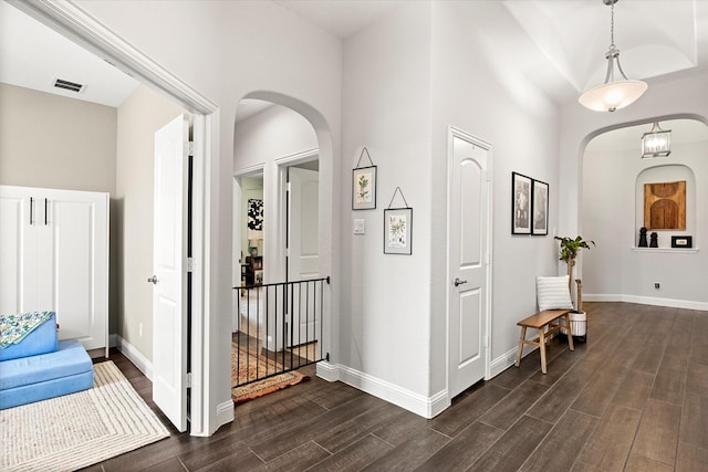 entrance foyer with arched walkways, dark wood-type flooring, baseboards, and a towering ceiling