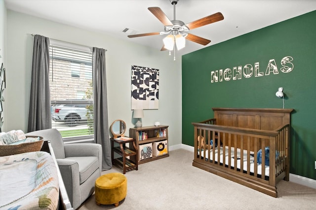 bedroom with a nursery area, carpet, a ceiling fan, and baseboards