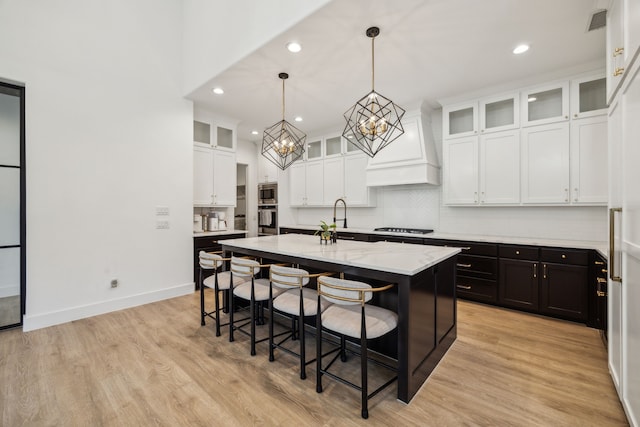 3791 Lockhart Dr, Prosper, TX 75078 - kitchen featuring stainless steel appliances, an island with sink, white cabinetry, custom range hood, and a chandelier