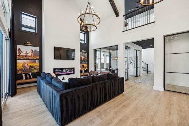 3791 Lockhart Dr, Prosper, TX 75078 - living area featuring a chandelier, light wood-style flooring, a towering ceiling, stairway, and a glass covered fireplace