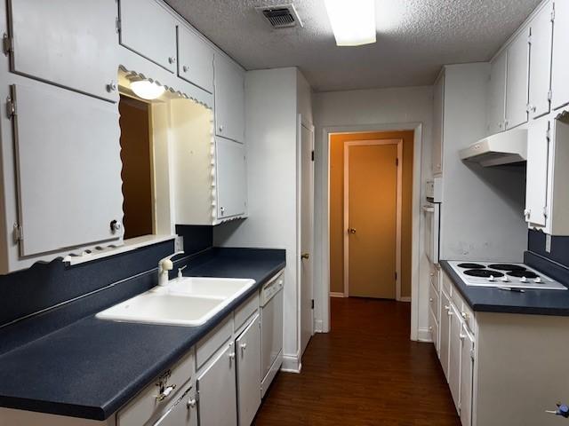 7625 Deaver Dr, North Richland Hills, TX 76180 - kitchen with under cabinet range hood, a sink, white appliances, a textured ceiling, and dark wood finished floors