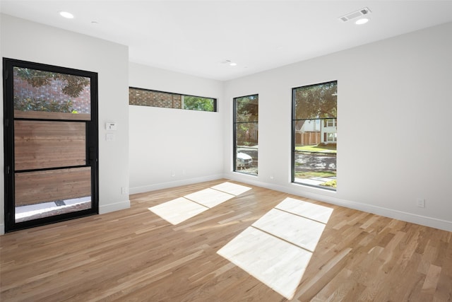 spare room featuring plenty of natural light, light wood-style flooring, baseboards, and recessed lighting