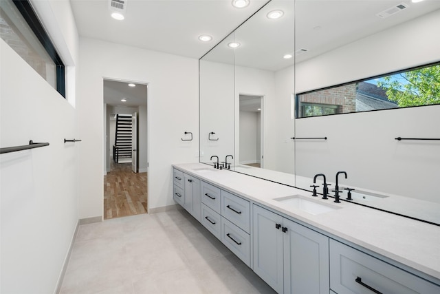 bathroom with double vanity, recessed lighting, and baseboards