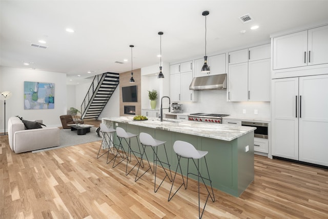 3512 Asbury St, University Park, TX 75205 - kitchen with a sink, light wood finished floors, under cabinet range hood, a kitchen bar, and white cabinetry
