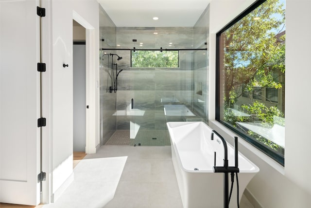 full bathroom with plenty of natural light, a shower stall, a freestanding tub, tile patterned flooring, and recessed lighting