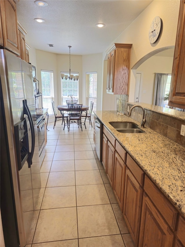 16 Cedar Bayou Cir, Pottsboro, TX 75076 - kitchen with appliances with stainless steel finishes, a sink, brown cabinetry, backsplash, and light stone countertops