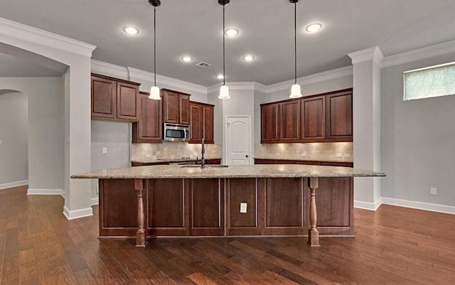 17015 Salado Dr, Woodway, TX 76712 - kitchen featuring stainless steel microwave, a sink, baseboards, arched walkways, and decorative backsplash