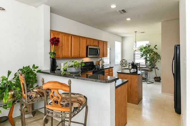 918 Telluride Dr, Arlington, TX 76001 - kitchen featuring black appliances, a kitchen island, brown cabinetry, a peninsula, and a textured ceiling