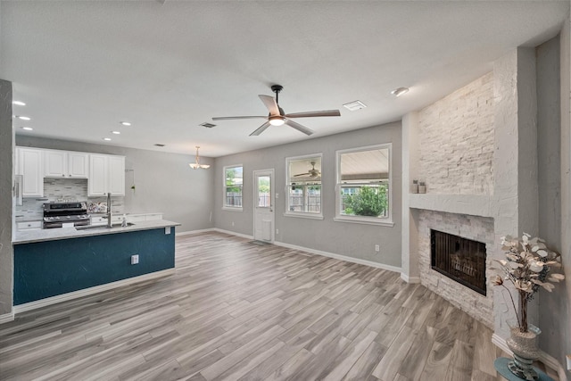 1612 Marble Cove Ln, Denton, TX 76210 - kitchen with stainless steel electric stove, a sink, a stone fireplace, ceiling fan, and open floor plan