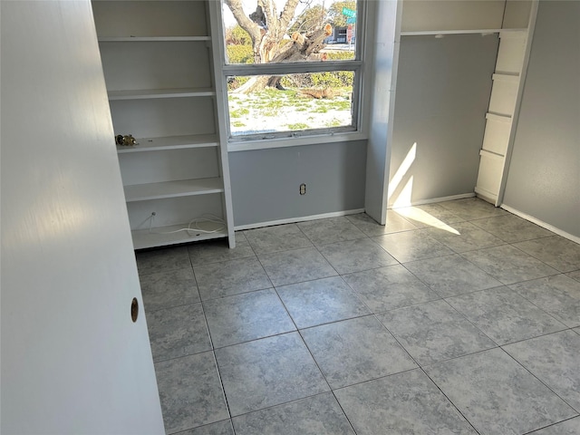 unfurnished bedroom featuring tile patterned flooring and baseboards