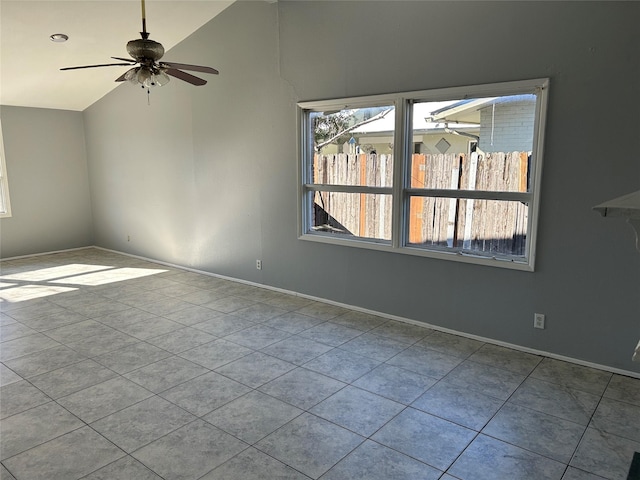 spare room with vaulted ceiling, ceiling fan, tile patterned floors, and baseboards