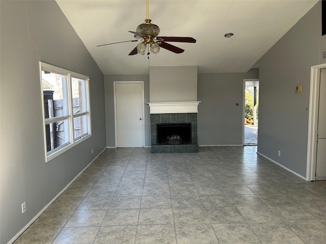 unfurnished living room with a ceiling fan, vaulted ceiling, a fireplace, baseboards, and light tile patterned flooring