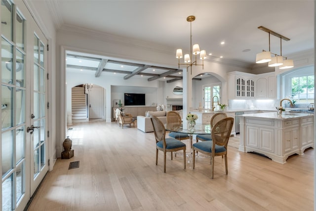 dining area with arched walkways, light wood-style flooring, french doors, beam ceiling, and recessed lighting