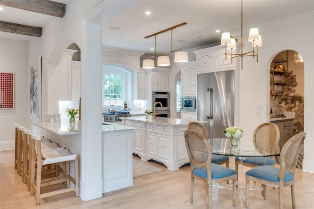 kitchen with stainless steel appliances, arched walkways, white cabinets, light wood-type flooring, and a peninsula