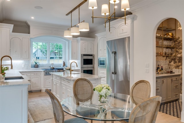 kitchen featuring stainless steel appliances, a sink, tasteful backsplash, light wood-style flooring, and white cabinets