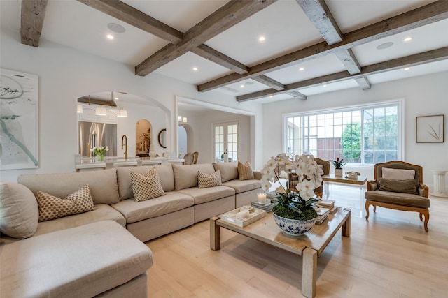 living area featuring arched walkways, beamed ceiling, coffered ceiling, light wood-type flooring, and recessed lighting