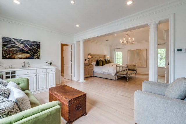 bedroom featuring decorative columns, light wood-style floors, ornamental molding, a sink, and recessed lighting