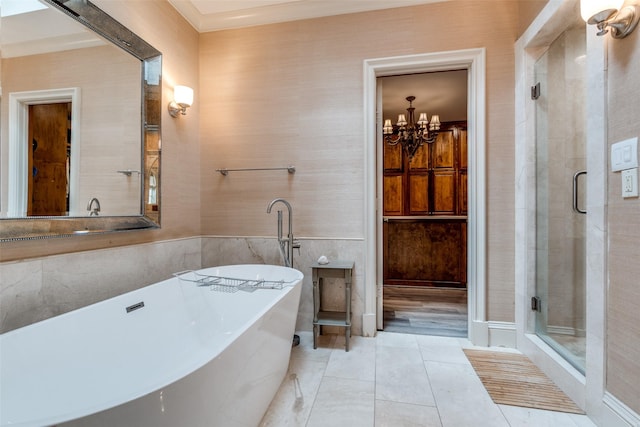 full bath with a freestanding bath, a chandelier, a stall shower, and tile walls