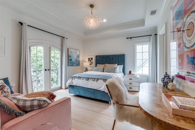 bedroom featuring multiple windows, ornamental molding, access to exterior, light wood-type flooring, and a tray ceiling