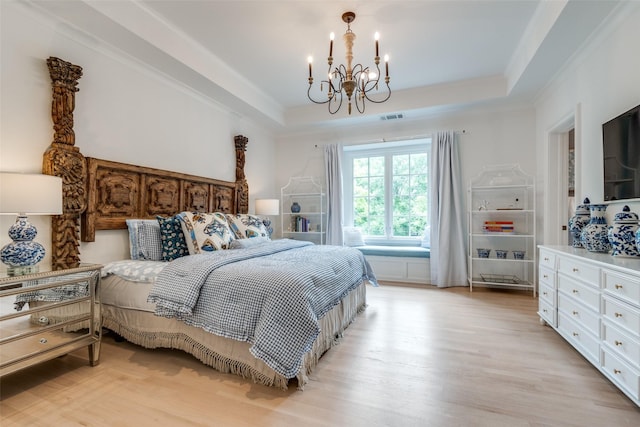 bedroom with a chandelier, a raised ceiling, and light wood finished floors