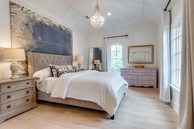 bedroom with a chandelier, light wood-style floors, ornamental molding, baseboards, and a tray ceiling