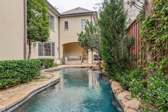 back of house with stucco siding and an outdoor pool