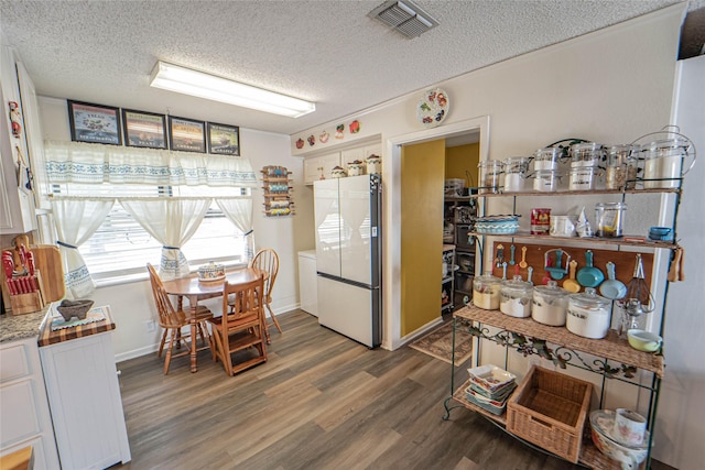 831 Plum St, Graham, TX 76450 - kitchen with freestanding refrigerator, a textured ceiling, wood finished floors, white cabinets, and light countertops