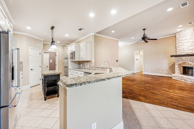 109 Rio Bravo Ct, Weatherford, TX 76088 - kitchen with stainless steel appliances, ornamental molding, light tile patterned flooring, ceiling fan, and a peninsula