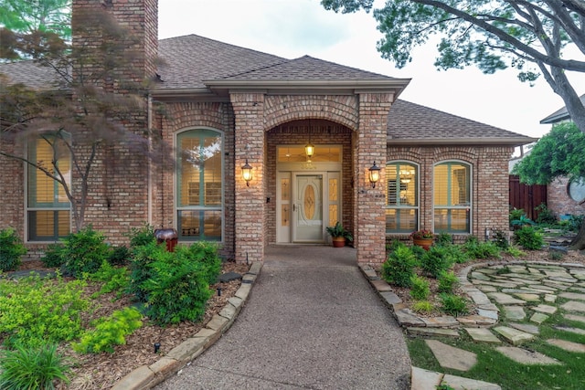 3824 Wyeth Dr, Plano, TX 75023 - view of exterior entry with a shingled roof, brick siding, and a chimney