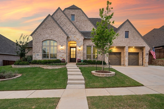 french country home featuring a lawn, brick siding, concrete driveway, and roof with shingles