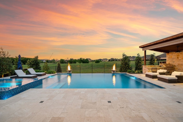pool at dusk featuring area for grilling, a patio, a fenced backyard, and outdoor lounge area