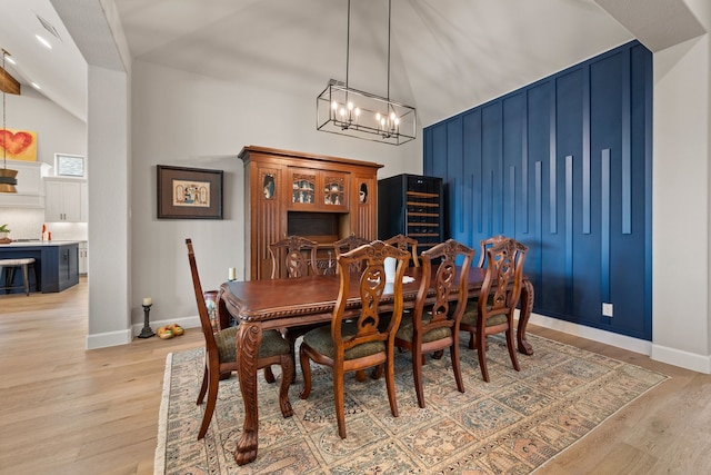 dining area featuring light wood-type flooring, a chandelier, baseboards, and a towering ceiling