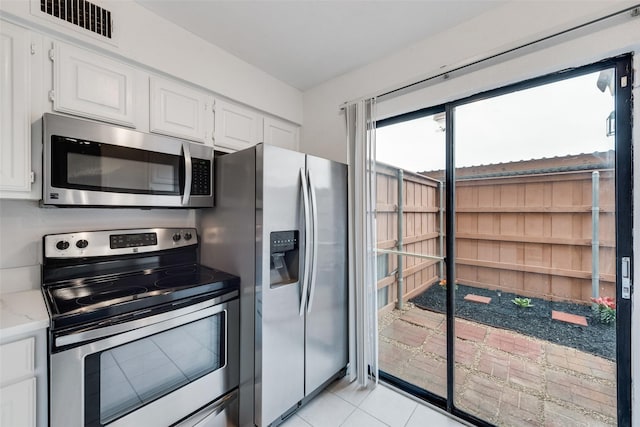 4325 Madera Rd, Irving, TX 75038 - kitchen with appliances with stainless steel finishes, white cabinetry, light stone counters, and light tile patterned flooring