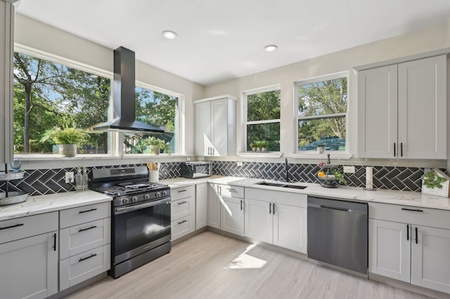 702 Griffith, Terrell, TX 75160 - kitchen featuring appliances with stainless steel finishes, wall chimney exhaust hood, a sink, tasteful backsplash, and light stone counters
