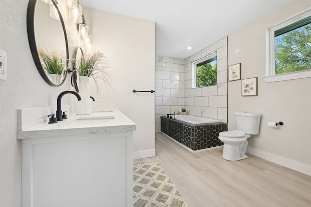 702 Griffith, Terrell, TX 75160 - bathroom with toilet, tiled bath, baseboards, wood finished floors, and double vanity