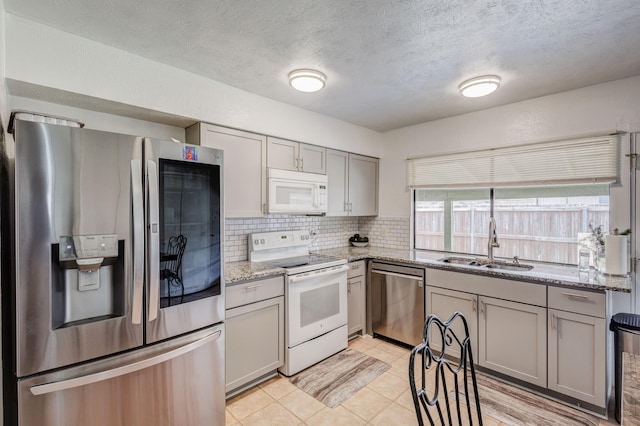 3110 Nutmeg Ln, Garland, TX 75044 - kitchen with appliances with stainless steel finishes, a sink, gray cabinetry, tasteful backsplash, and a textured ceiling