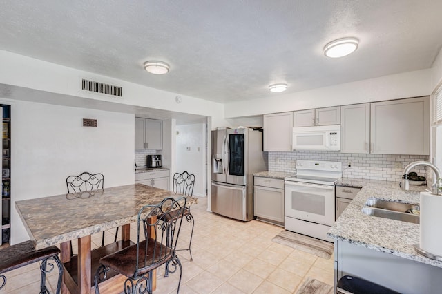 3110 Nutmeg Ln, Garland, TX 75044 - kitchen with white appliances, a sink, gray cabinets, backsplash, and light stone countertops