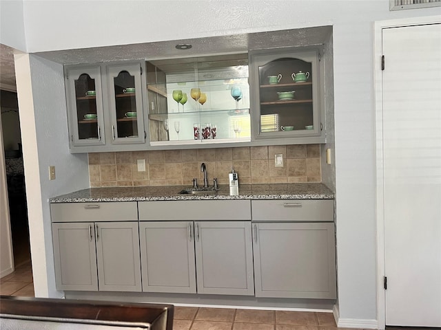 3110 Nutmeg Ln, Garland, TX 75044 - bar area featuring a sink, decorative backsplash, light tile patterned floors, and baseboards