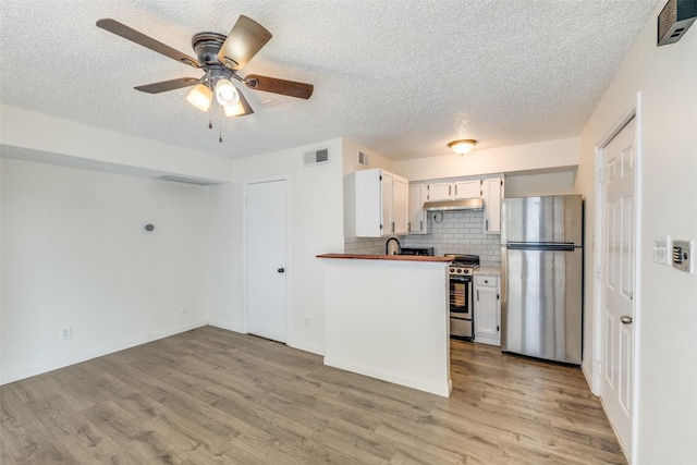 2301 Balsam Dr Unit F308, Arlington, TX 76006 - kitchen featuring appliances with stainless steel finishes, a textured ceiling, light wood-type flooring, white cabinets, and under cabinet range hood