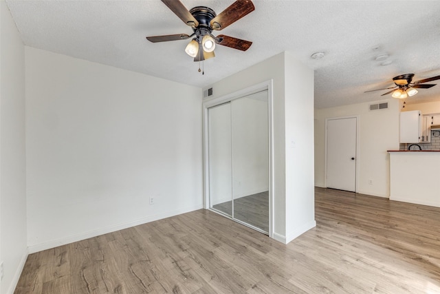 2301 Balsam Dr Unit F308, Arlington, TX 76006 - unfurnished bedroom featuring light wood-style flooring, a closet, a textured ceiling, a ceiling fan, and baseboards