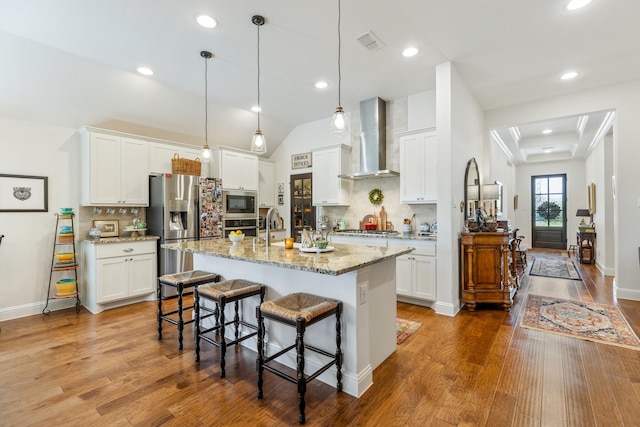 821 Mildren Ln, Fate, TX 75087 - kitchen with wall chimney exhaust hood, stainless steel appliances, decorative backsplash, wood finished floors, and recessed lighting
