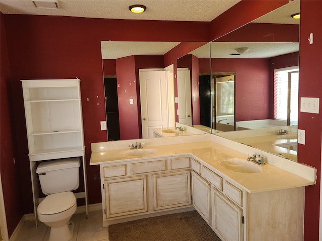 full bathroom featuring tile patterned floors, toilet, double vanity, baseboards, and a textured ceiling