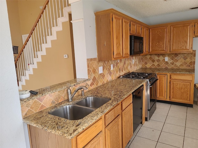 kitchen featuring black appliances, a sink, tasteful backsplash, light stone countertops, and a textured ceiling