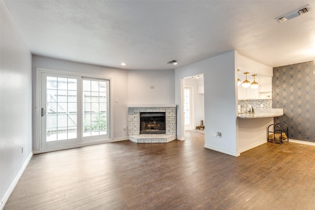2330 Kennington Dr Unit D, Arlington, TX 76012 - unfurnished living room with dark wood finished floors, baseboards, a fireplace with raised hearth, and recessed lighting