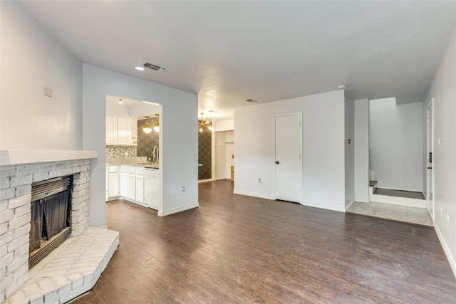 2330 Kennington Dr Unit D, Arlington, TX 76012 - unfurnished living room with a brick fireplace, a sink, dark wood finished floors, baseboards, and recessed lighting