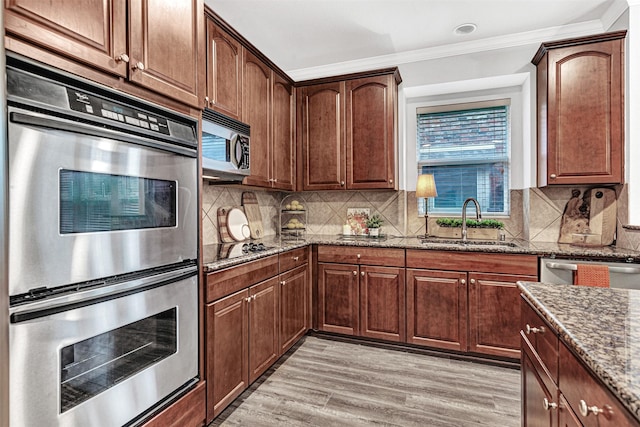 1600 Templegate Dr, Mckinney, TX 75072 - kitchen featuring appliances with stainless steel finishes, a sink, dark stone countertops, light wood-style floors, and ornamental molding